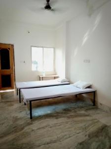 Dos camas sentadas en una habitación con ventana. en MONIKA MANSION Bodhgaya, en Bodh Gaya