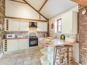 eine Küche mit weißen Schränken und einer Theke mit Stühlen in der Unterkunft The Forge - Uk37519 in Routh