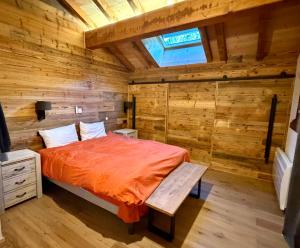 ein Schlafzimmer mit einem Bett in einem Zimmer mit Holzwänden in der Unterkunft Le Refuge d'Ours, Champagny in Champagny-en-Vanoise