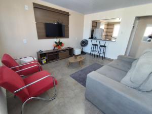 a living room with a couch and red chairs at Apto Dom Pedrito in Dom Pedrito