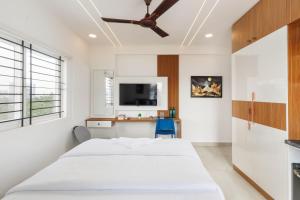 a white bedroom with a bed and a desk at OBS Luxury Suites - JP Nagar in Bangalore
