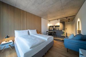 a bedroom with a large bed and a blue couch at Aparthotel Il Momento Bern Expo - Self Check-In Hotel in Bern