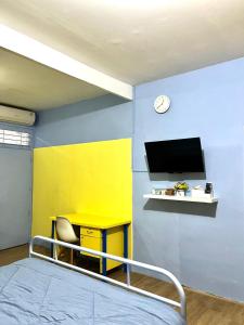 a room with a bed and a desk and a tv at Zona Bobo Yellow Cream Cheese Moslem Friendly By Belgareti in Cimareme