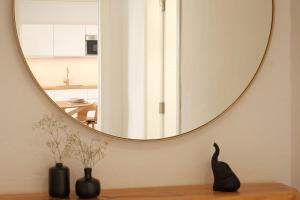 a round mirror on a wall with two vases on a table at Finca el Moral by Huskalia in Los Llanos de Aridane