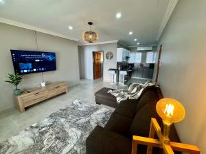 a living room with a couch and a flat screen tv at Urban Bliss Villa in Klerksdorp