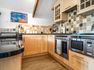 a kitchen with wooden cabinets and stainless steel appliances at Raddons - Uk50657 in Crackington Haven