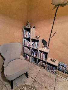 Una habitación con una silla y una estantería con libros. en Saisonnée, en Centrès