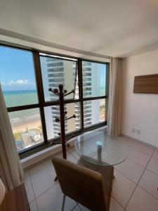 comedor con mesa de cristal y algunas ventanas en Beach Class Executive por Yolo, en Recife