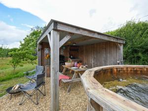 a wooden building with a pond next to a table and a chair at The Sheep Pod - Uk50074 in Welshpool