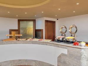 a buffet with food on a counter with two mirrors at B&B HOTEL Alba in Alba