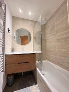 Chalet rénové, charme montagnard et confort moderne في لو ديفولي: حمام مزود بحوض استحمام ومغسلة ومرآة