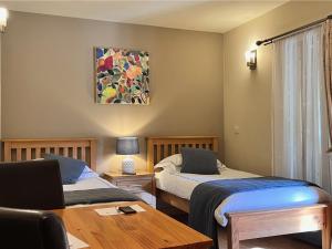 two beds in a room with a desk and a table at Orchard Cottage in Willingham