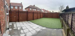 a backyard with a fence and a green lawn at Whitford living 1 South Shields in West Boldon