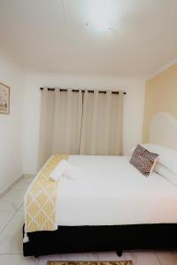 a bedroom with a white bed and a window at Brytelight Luxe in Rustenburg