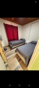 two beds in a room with red curtains at Hospedaje la querencia in San Antonio de Areco