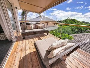 a deck with two chairs and an umbrella on a balcony at Villa Olive Sea View Cocoon in Oyster Pond in Oyster Pond