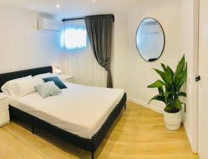 a bedroom with a bed with a mirror and a plant at 101 - Beachside Renovated 1BR apt w private garden in Cambrils