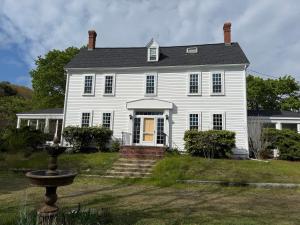 an old white house with a fountain in the yard at The Copper Swan in Wellfleet +35 photos