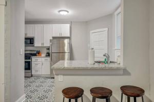 a kitchen with white cabinets and a counter with stools at Beautiful Brand New Tower Grove Unit 1s in Clifton Heights