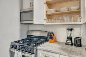 a kitchen with a stove and white cabinets at Beautiful Brand New Tower Grove Unit 1s in Clifton Heights