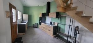a large kitchen with green walls and wooden stairs at la petite écurie in Soleymieu