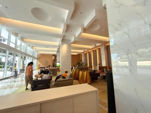 a lobby of a building with people sitting in chairs at Apartment Podomoro Lincoln Delipark in Medan