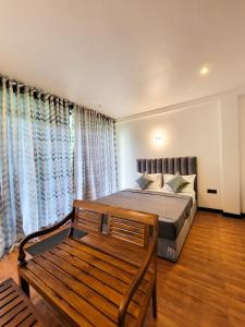 a bedroom with a bed and a bench and curtains at Shenu Villa in Talpe