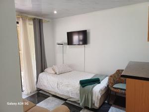 a small bedroom with a bed and a tv on the wall at Perdehoek Venue in Lichtenburg
