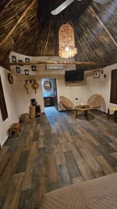 a large room with a wooden floor and a chandelier at Cabañas Los Gallitos Ecolodge 3 in Sacalum