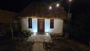 a small white house with a straw roof at night at Cabañas Los Gallitos Ecolodge 3 in Sacalum