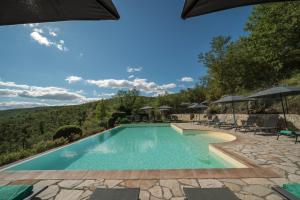 a swimming pool with chairs and umbrellas on a patio at Borgo Le Noci Chianti Retreat & Pool in Gaiole in Chianti