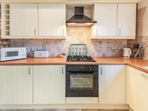 eine Küche mit weißen Schränken und einem Herd mit Backofen in der Unterkunft The Forge - Uk37519 in Routh + 16 Fotos