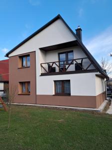 a white and brown house with a balcony at Domek w górach Wioletta in Rycerka Górna