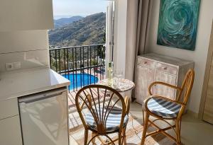 a kitchen with a table and chairs and a balcony at Casa Bella Vista in Cómpeta