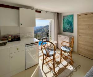 a kitchen with two chairs and a table with a balcony at Casa Bella Vista in Cómpeta