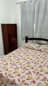 1 Schlafzimmer mit einem Bett mit Blumenbettdecke und einer Kommode in der Unterkunft Casa para o Natal in Garanhuns