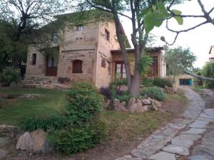 an old stone house with a tree in front of it at Casa Amarilla in Mina Clavero