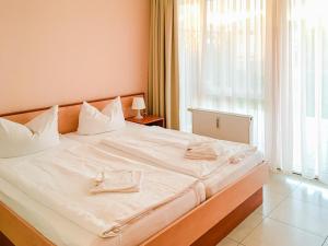 a bedroom with a bed with white sheets and a window at Residenz Meeresblick D Fewo E5 in Rerik +12 photos