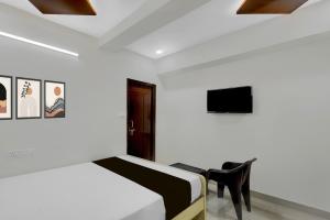 a bedroom with a bed and a chair at Hotel O De' BVL Grand in Hyderabad