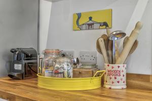 a yellow container on a counter with wooden utensils at Priory Coach House in Pagham +69 photos