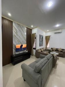 ein Wohnzimmer mit Sofas und einem großen TV in der Unterkunft Casa de Bella BnB in Mataram