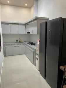 eine Küche mit einem schwarzen Kühlschrank und weißen Schränken in der Unterkunft Casa de Bella BnB in Mataram