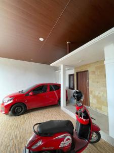 Ein roter Roller parkt in einer Garage neben einem roten Auto. in der Unterkunft Casa de Bella BnB in Mataram + 5 Fotos