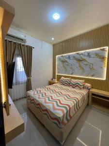 ein Schlafzimmer mit einem Bett mit einem großen Gemälde an der Wand in der Unterkunft Casa de Bella BnB in Mataram