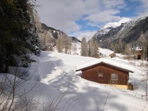 a cabin covered in snow with mountains in the background at Ferienbungalows MOHR in Sankt Jakob in Defereggen