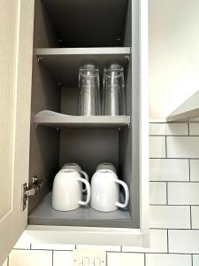 deux bocaux Mason et deux tasses dans un placard de cuisine dans l'établissement Brain Properties Limited - Garden flat with Parking near QA Hospital, à Portsmouth