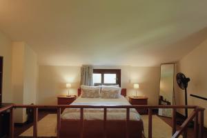 a bedroom with a bed with two lamps and a window at Casa da Alvarinha. Privacidade, Conforto, Natureza in Paredes