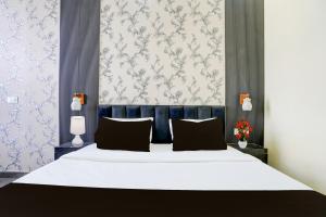 a bedroom with a large white bed with black pillows at Hotel O Raj Ambessy in Rāmpura