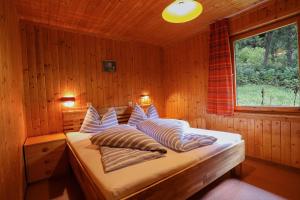a bedroom with a bed with pillows and a window at Ferienbungalows MOHR in Sankt Jakob in Defereggen
