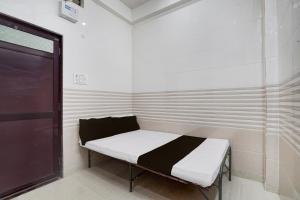 a small bed in a room with a door at SPOT ON Radhakund Guest House in Rādha Kund